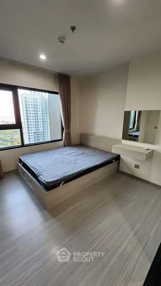 Modern bedroom with large window and minimalist design in urban apartment.