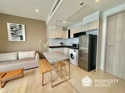 Modern open-plan living room with kitchen, featuring sleek appliances and stylish decor.