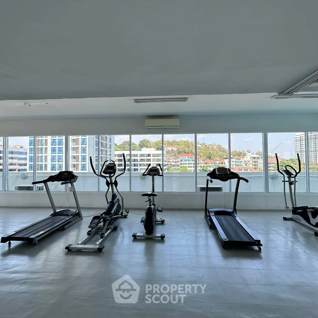 Spacious gym with modern equipment and panoramic city views, perfect for fitness enthusiasts.