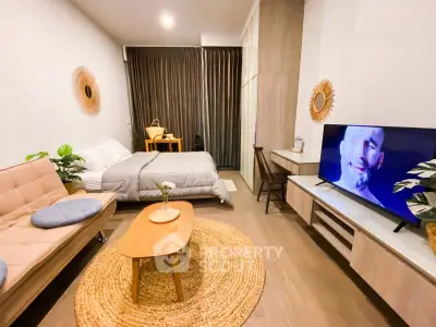 Modern studio apartment with cozy decor and large TV, perfect for urban living.