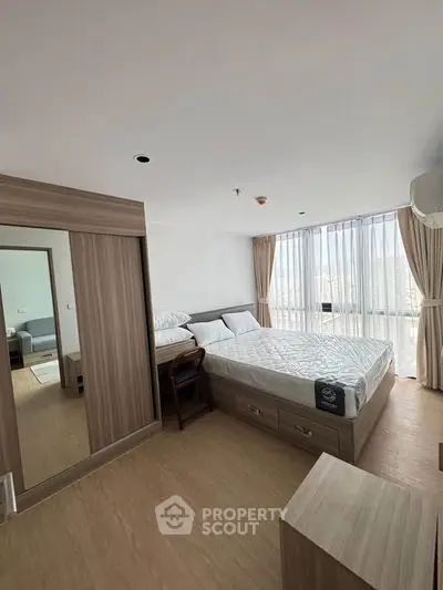 Modern bedroom with large windows and wooden flooring in a stylish apartment.