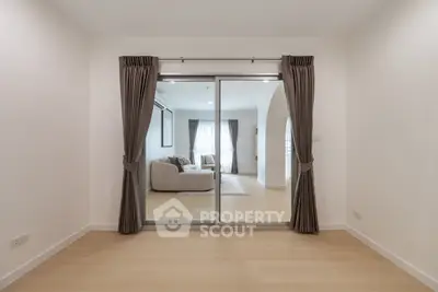 Spacious modern living room with sliding glass doors and elegant curtains, showcasing a cozy seating area.