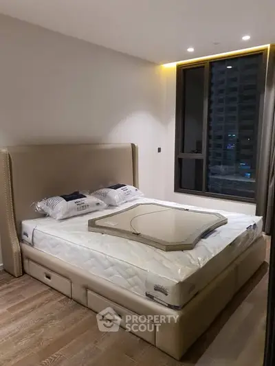 Modern bedroom with stylish bed and large window offering city view