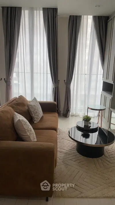 Stylish living room with elegant curtains, cozy brown sofa, and modern coffee table in a bright apartment.