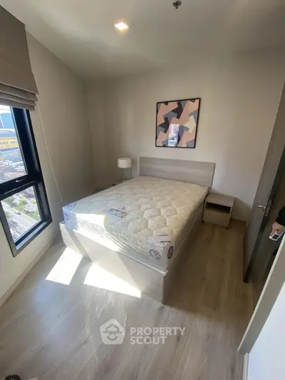 Cozy bedroom with natural light, modern decor, and city view, perfect for urban living.