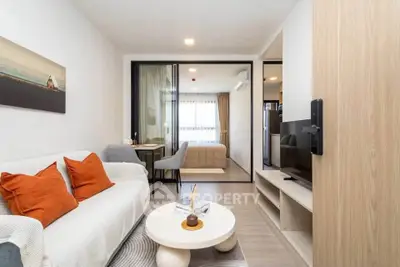 Modern living room with cozy sofa and stylish decor leading to a bright bedroom.