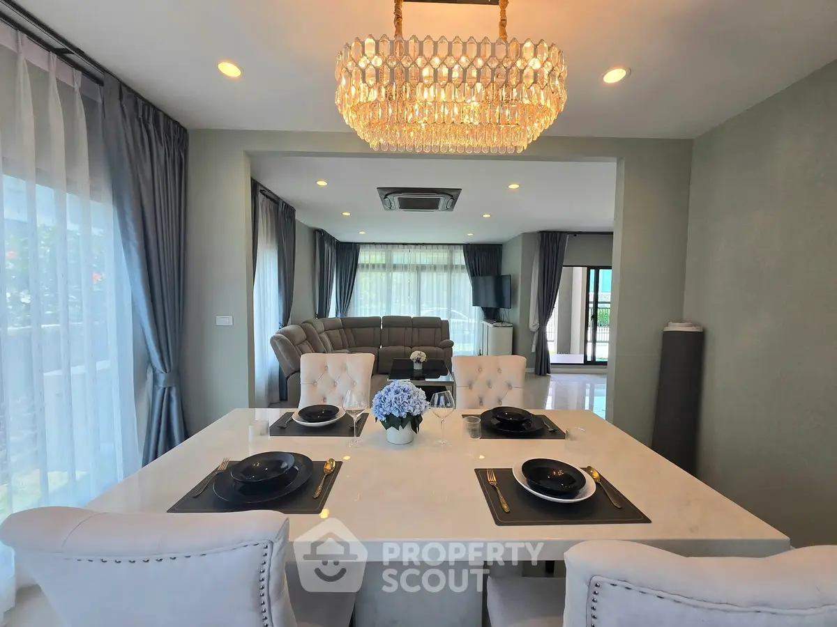 Luxurious dining area with elegant chandelier and spacious living room view