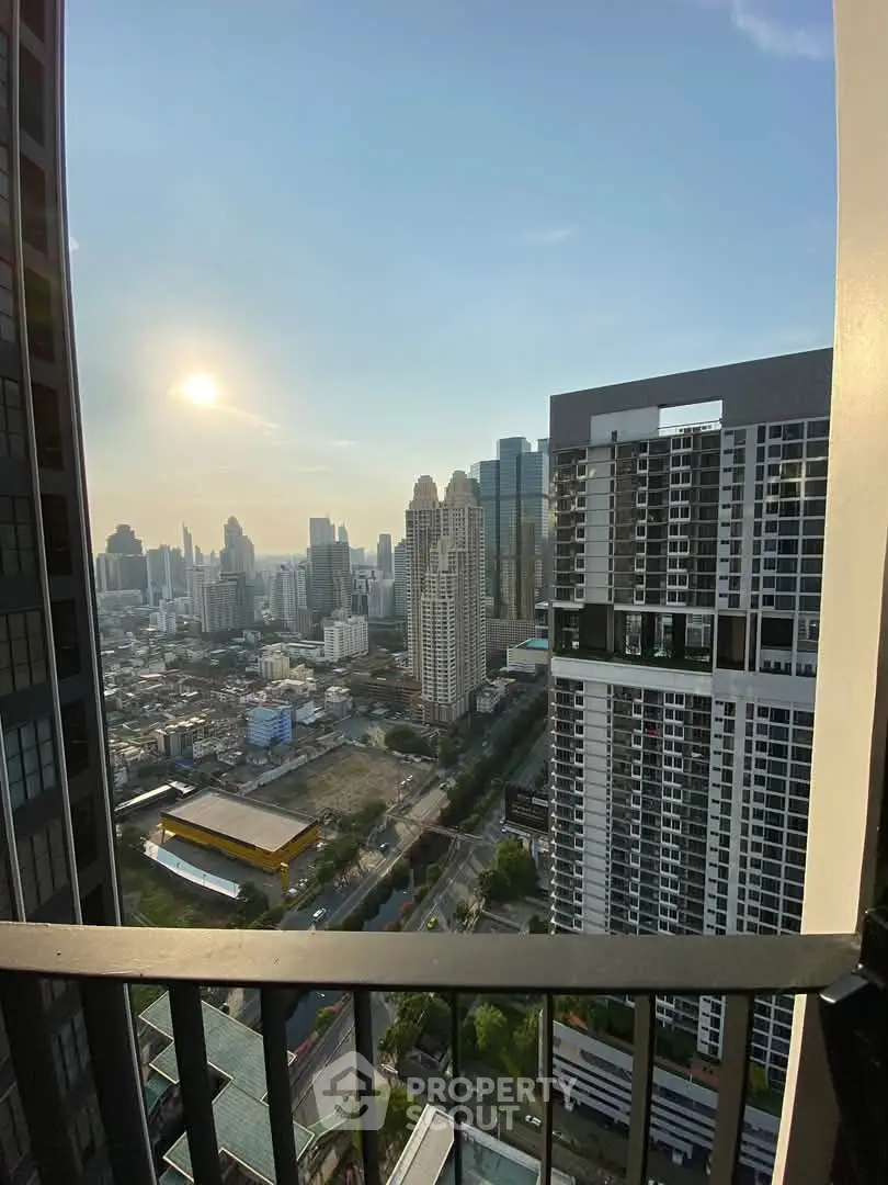 Stunning cityscape view from a high-rise balcony, showcasing modern urban living with skyscrapers and sunset.