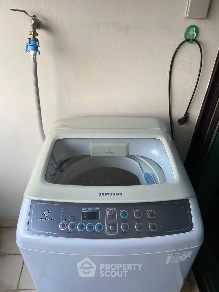 Modern Samsung washing machine in a laundry area with water connection.
