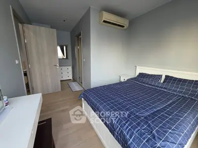 Modern bedroom with blue checkered bedding and air conditioning, featuring sleek wooden flooring and neutral walls.