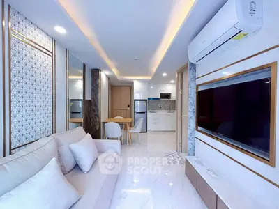 Modern living room with sleek design, featuring a large TV, stylish sofa, and open kitchen layout.