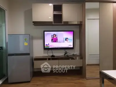 Modern living room with sleek TV setup and refrigerator, perfect for urban living.