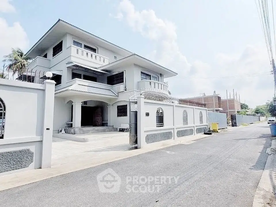 Stunning three-story villa with elegant facade and spacious driveway in a serene neighborhood.