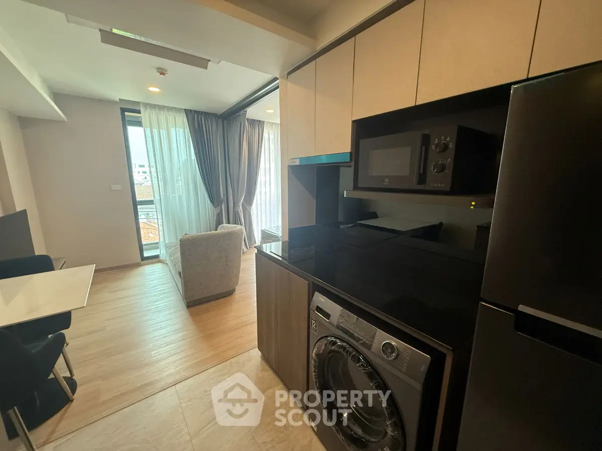 Modern open-plan living room with kitchen featuring washing machine and microwave.