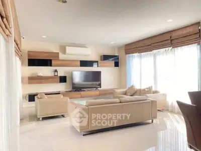 Spacious modern living room with elegant beige sofas and large windows for natural light.