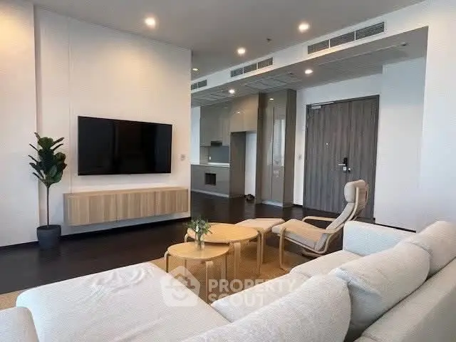 Spacious modern living room with sleek furniture and large TV, perfect for relaxation and entertainment.