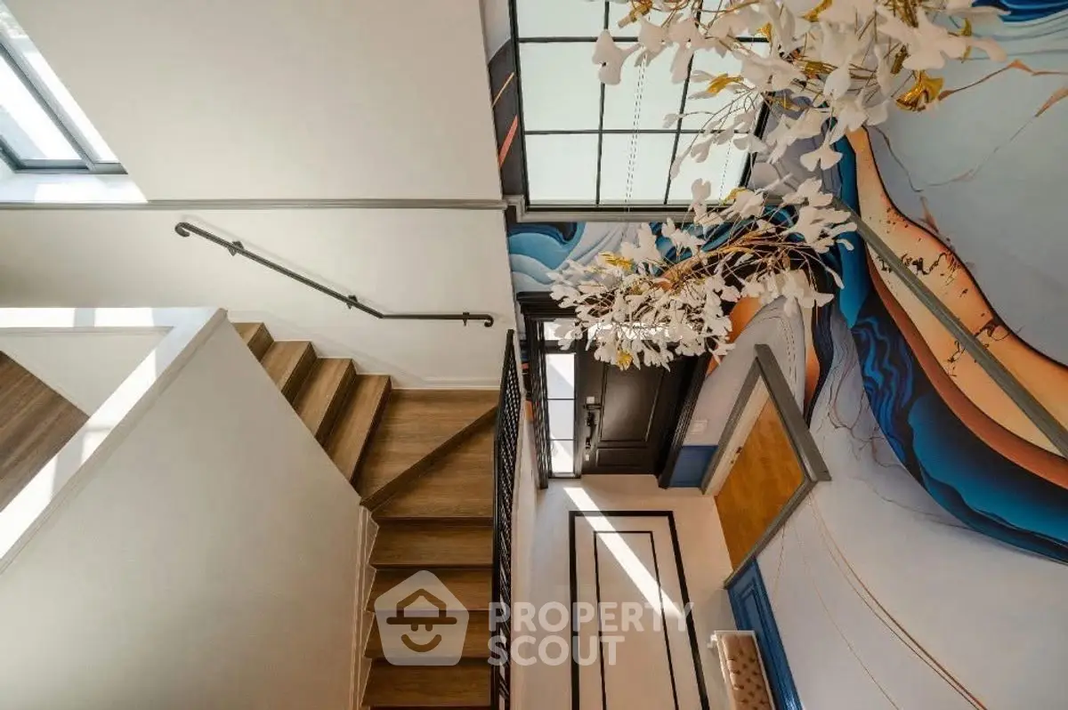 Stylish modern entrance with artistic wall design and wooden staircase