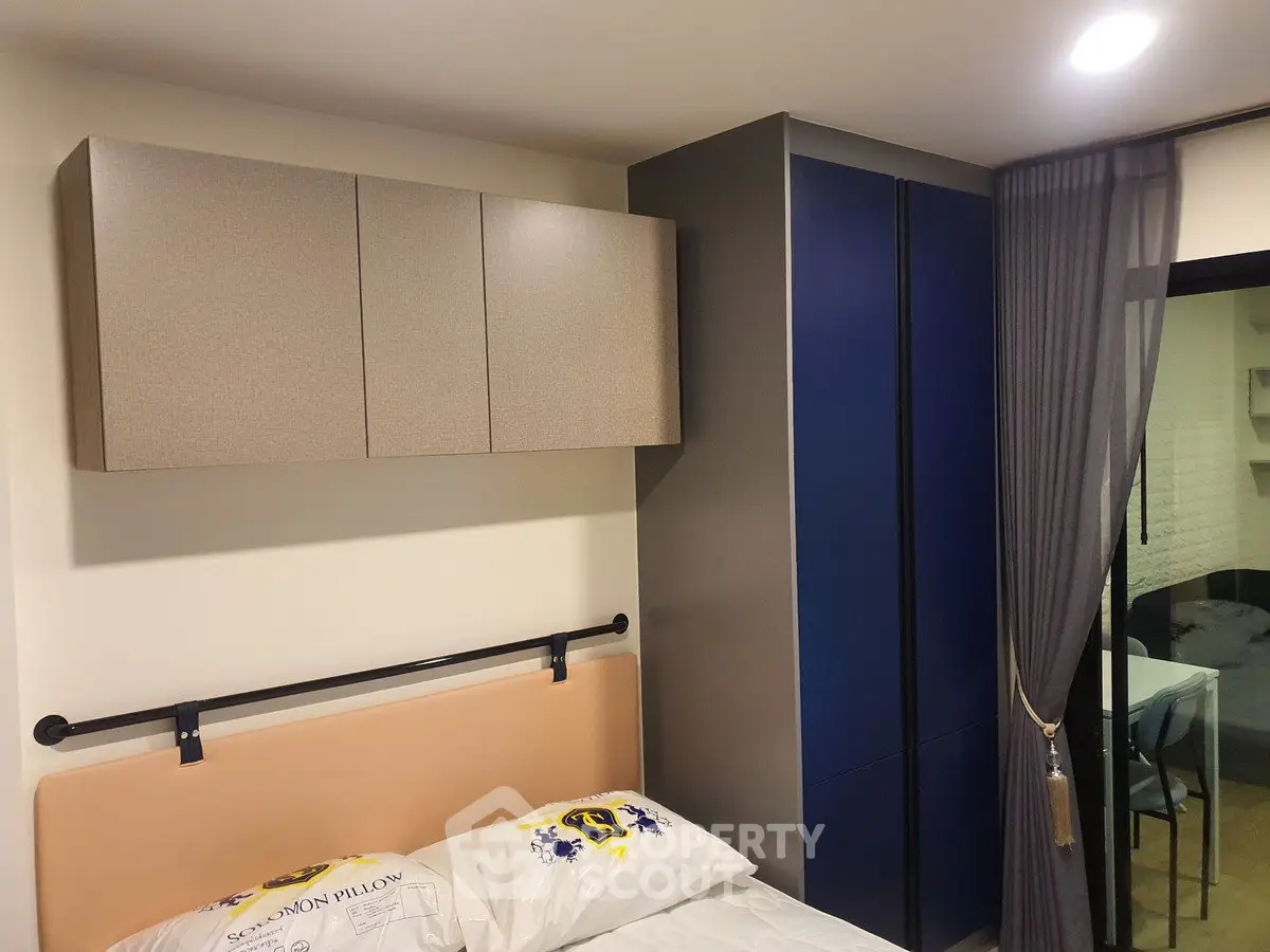 Modern bedroom with sleek storage and sliding glass door to study area.