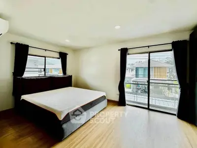 Spacious bedroom with large windows and modern decor in a bright, airy home.