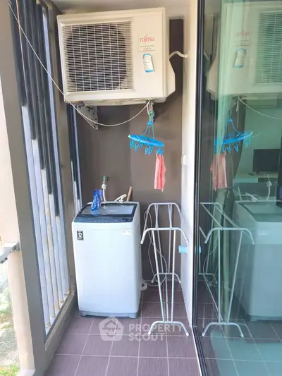 Compact balcony with washing machine and air conditioning unit in modern apartment.
