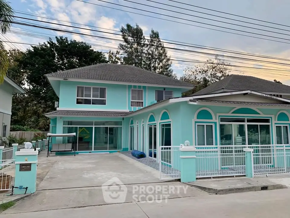Charming turquoise two-story house with spacious driveway and modern design.