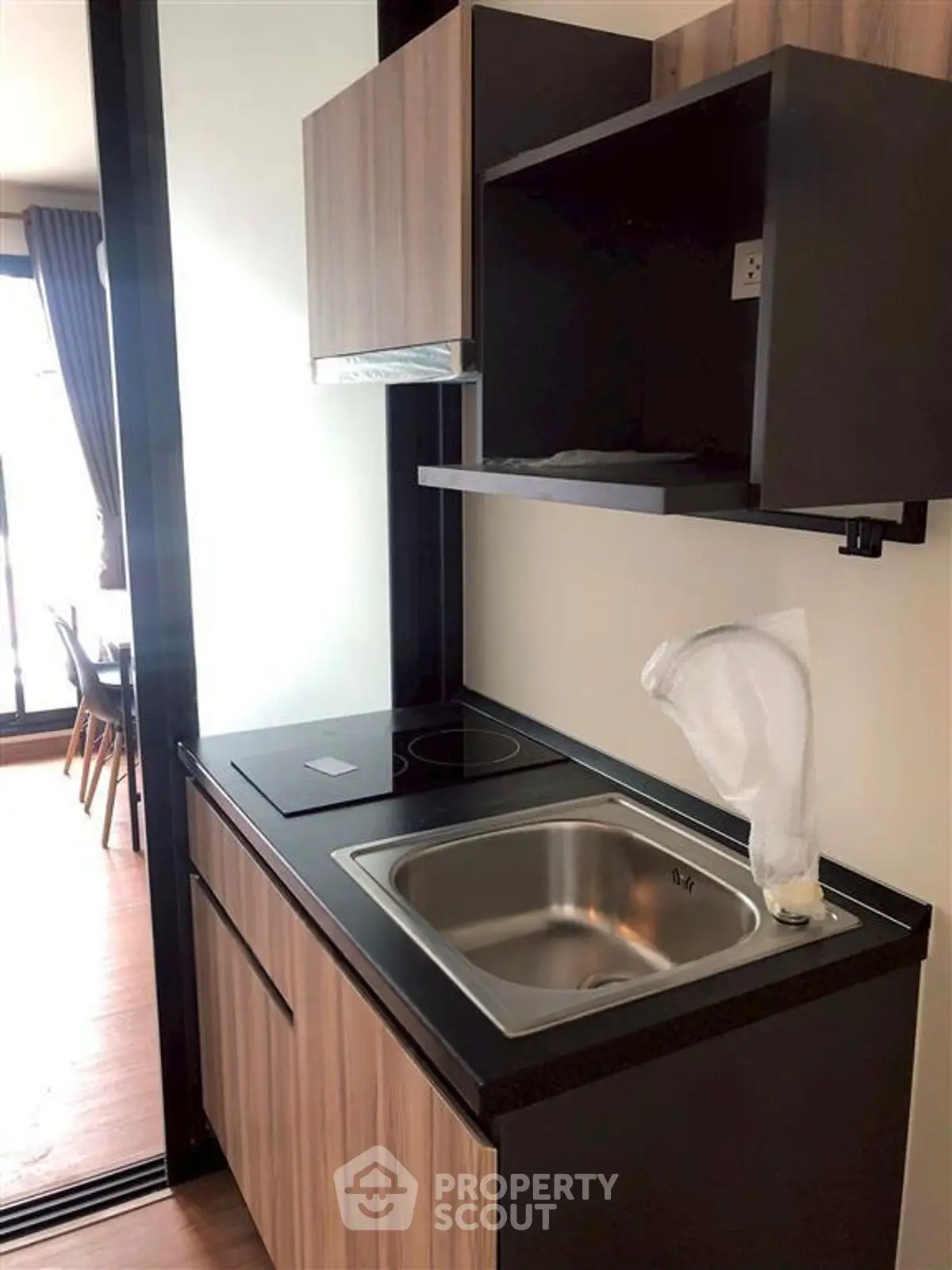 Modern compact kitchen with sleek cabinetry and electric cooktop in a stylish apartment.