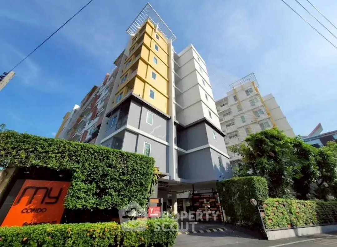 Modern condo building with vibrant facade and lush greenery