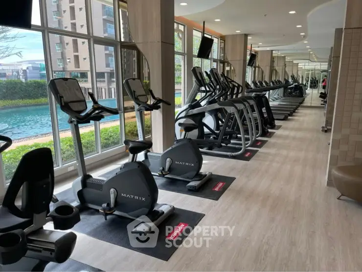 Modern gym with cardio equipment and large windows overlooking a scenic view.