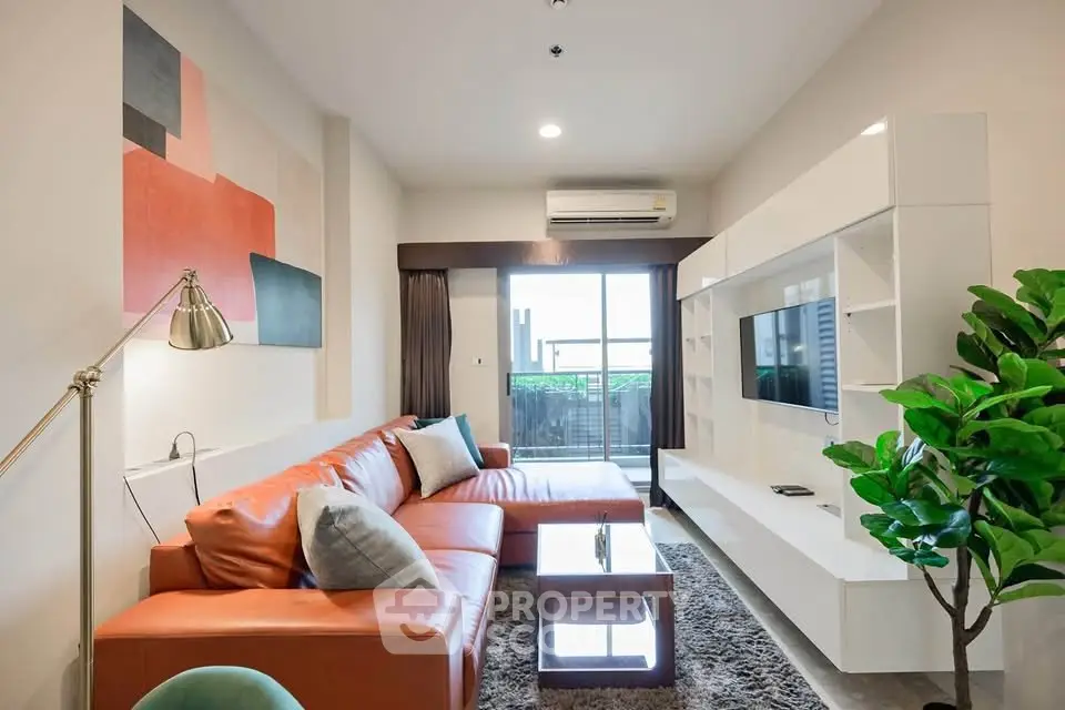 Modern living room with stylish decor and large sofa, featuring a balcony view.