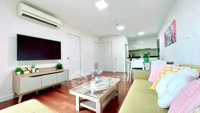 Bright and modern living room with open kitchen layout, featuring stylish decor and hardwood floors.