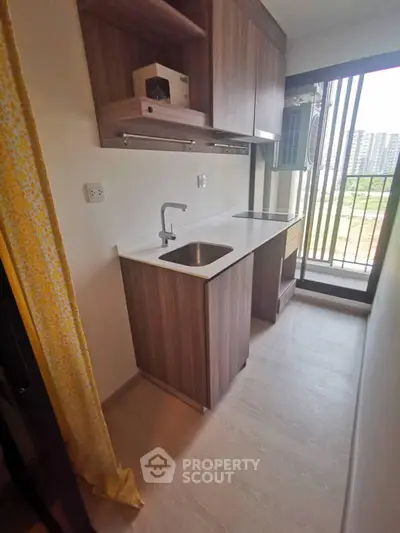 Compact kitchen with modern cabinetry and balcony view in urban apartment