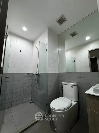 Modern bathroom with sleek design, featuring a glass-enclosed shower and contemporary fixtures.