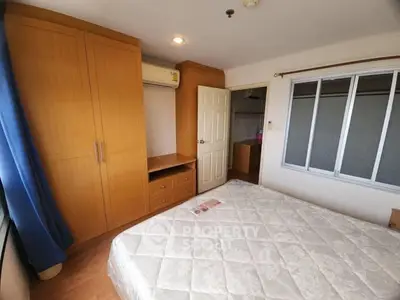 Cozy bedroom with wooden wardrobe and large window for natural light