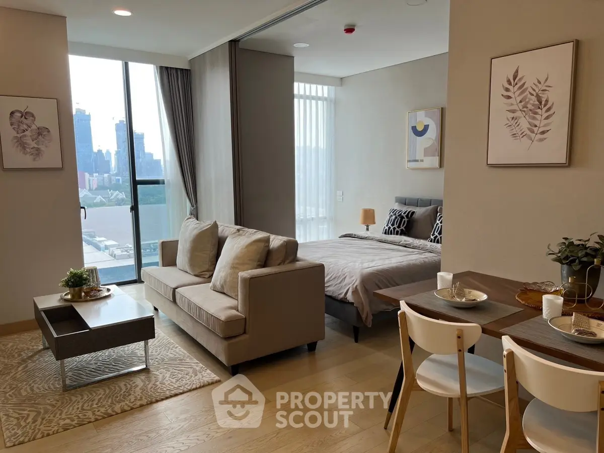Modern open-plan living room and bedroom with city view, stylish decor, and natural light.
