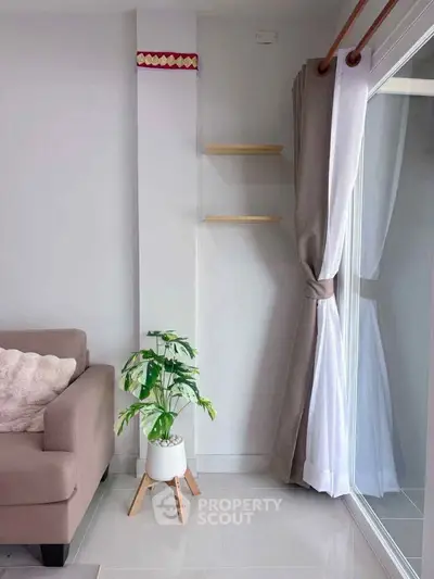 Modern living room with stylish sofa, potted plant, and large window with elegant curtains.