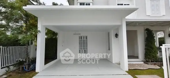 Modern white house exterior with covered carport and lush greenery