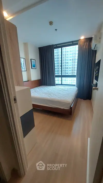 Modern bedroom with large window and wooden flooring in high-rise apartment