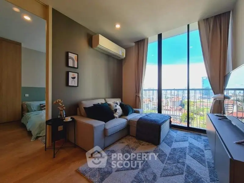 Modern living room with large windows and city view, featuring cozy sofa and stylish decor.