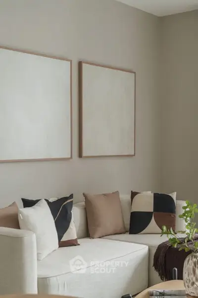 Modern living room with stylish decor and neutral tones, featuring abstract art and cozy seating.