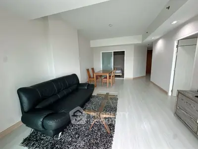 Spacious living room with modern black leather sofa and elegant dining area.