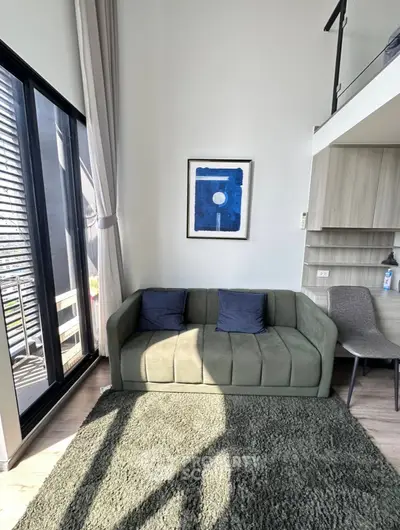 Modern living room with high ceiling and mezzanine, featuring a stylish sofa and large window for natural light.