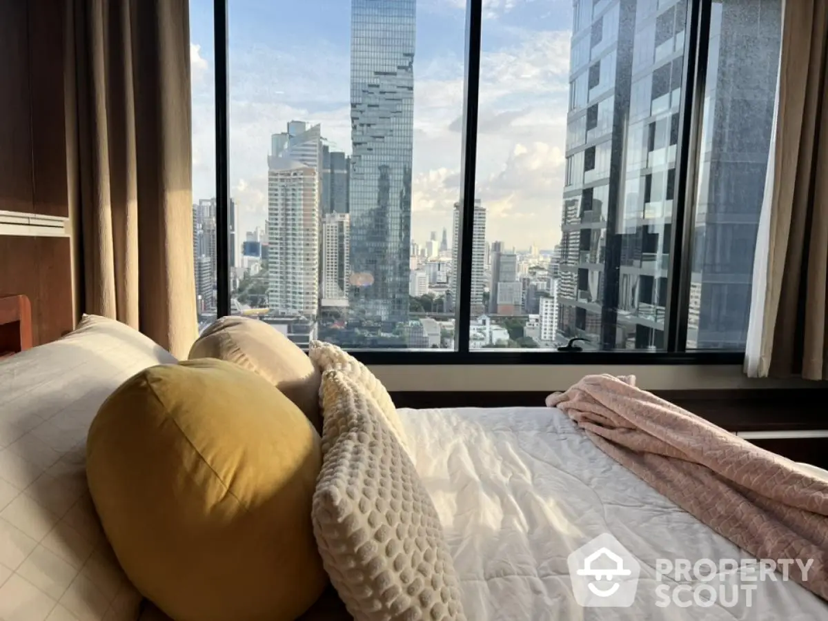 Luxurious bedroom with stunning city view from large window in high-rise apartment.