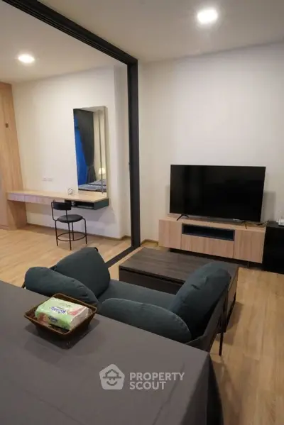 Modern living room with sleek TV setup and cozy seating in stylish apartment.