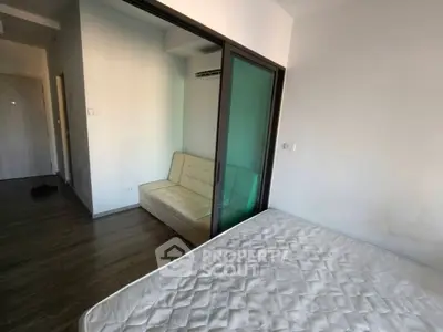 Modern bedroom with sliding glass partition and cozy sofa in a minimalist apartment.