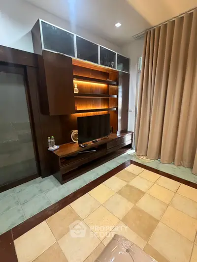 Spacious living room with modern wooden entertainment center and large windows.