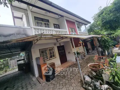 Charming two-story house with covered carport and lush garden area, perfect for family living.