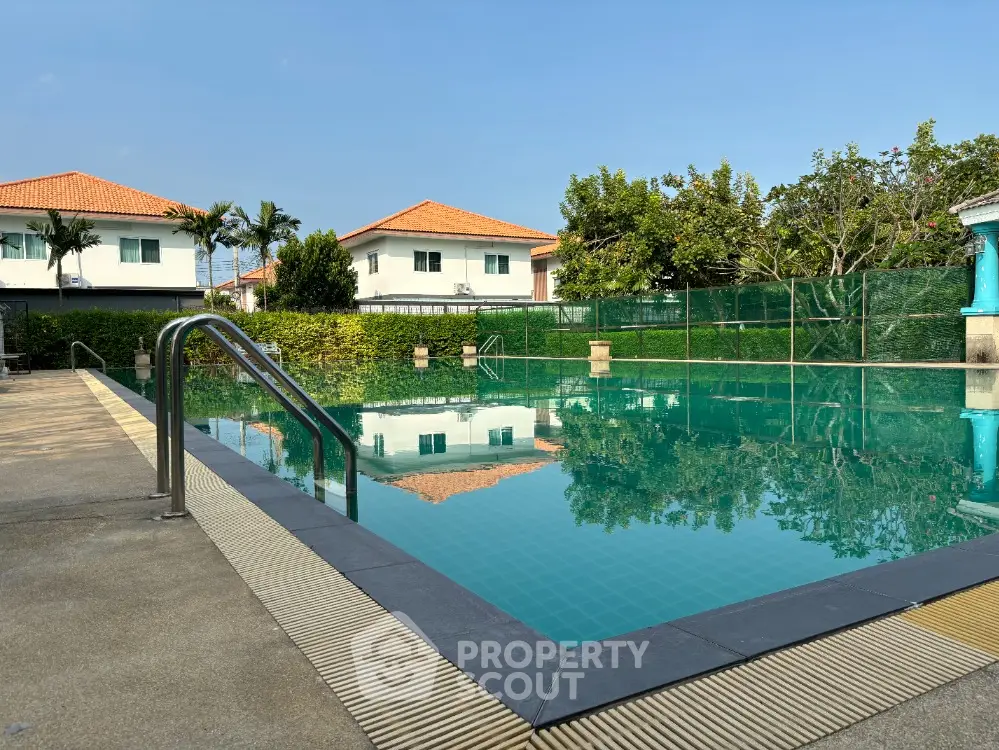 Stunning residential pool area with clear blue water and lush greenery, perfect for relaxation and leisure.