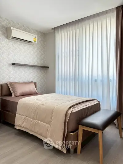 Cozy bedroom with modern decor and natural light, featuring a single bed and air conditioning.