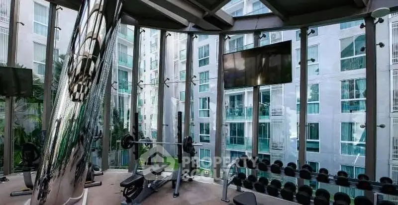 Modern gym with floor-to-ceiling windows offering stunning views of urban architecture.