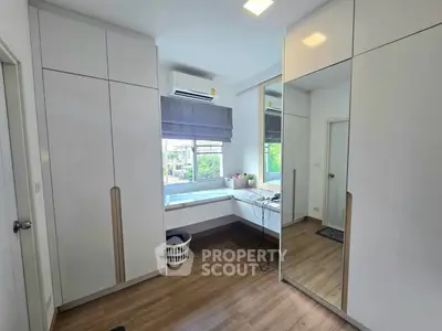 Modern bedroom with built-in wardrobes and large window offering natural light.